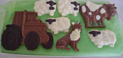 a picture of a milk chocolate farm animals and tractor, decorated with white and dark chocolate